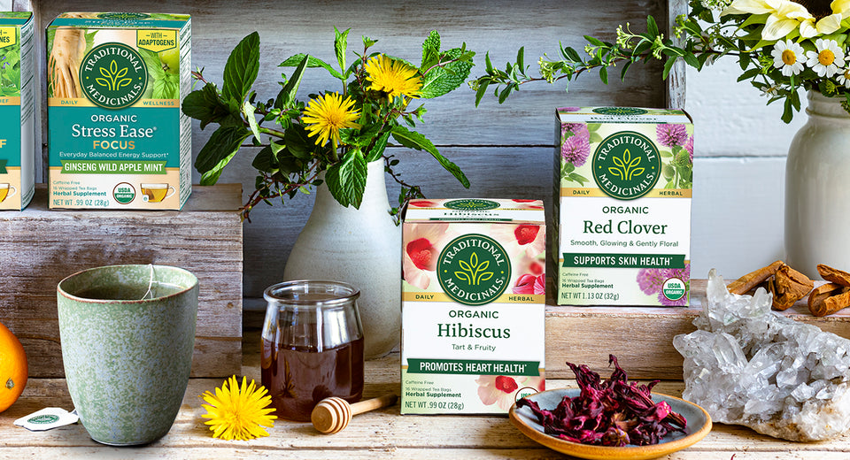 Traditional Medicinals tea boxes, brewed tea, flowers, and other items on a table