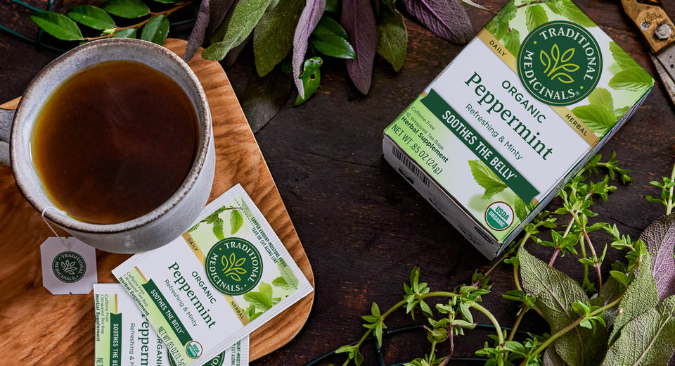 Peppermint tea next to fresh peppermint leaves and steeping mug